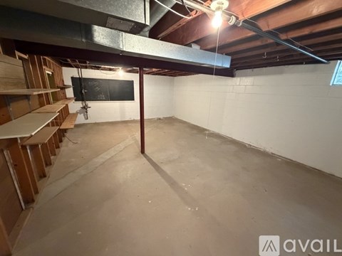 A spacious, unfinished basement with a blackboard on the wall.