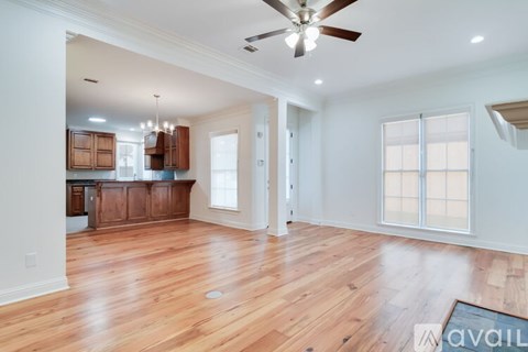 A spacious room with wooden floors and a ceiling fan.