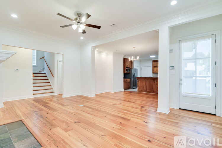 A spacious living room with wooden flooring and a ceiling fan.
