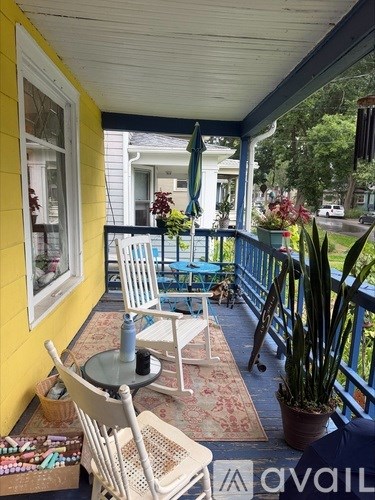 A yellow house with a balcony has a table and chairs on it.