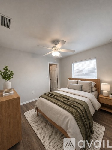 A bedroom with a bed, a ceiling fan, and a nightstand with a plant on it.