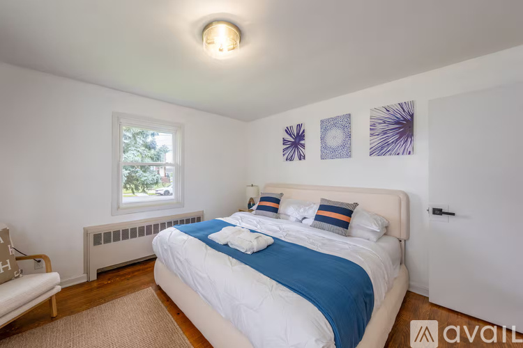 A bedroom with a white bed and a window with a view of trees outside.