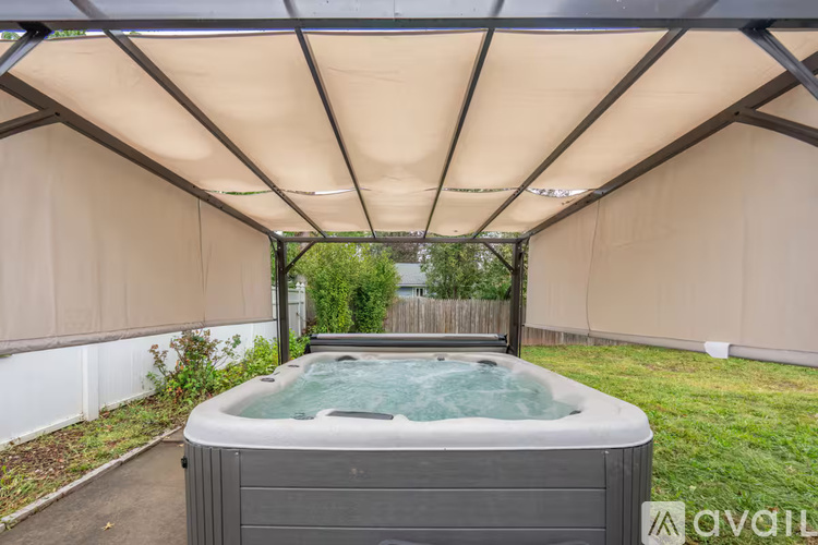 A hot tub is located under a canopy in a backyard.