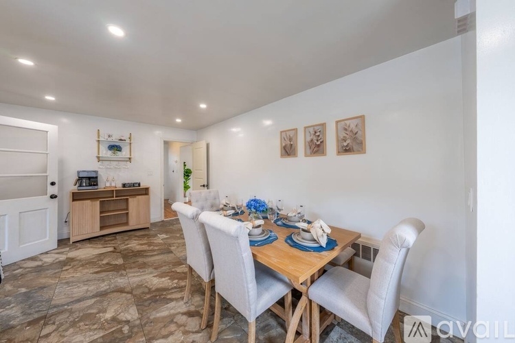 A dining room with a table set for two and a white chair.