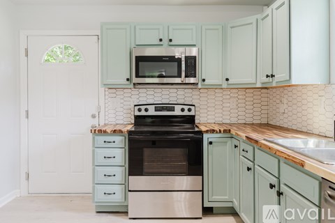 A kitchen with green cabinets and a white door.