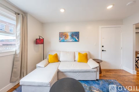 A living room with a white couch and a painting on the wall.