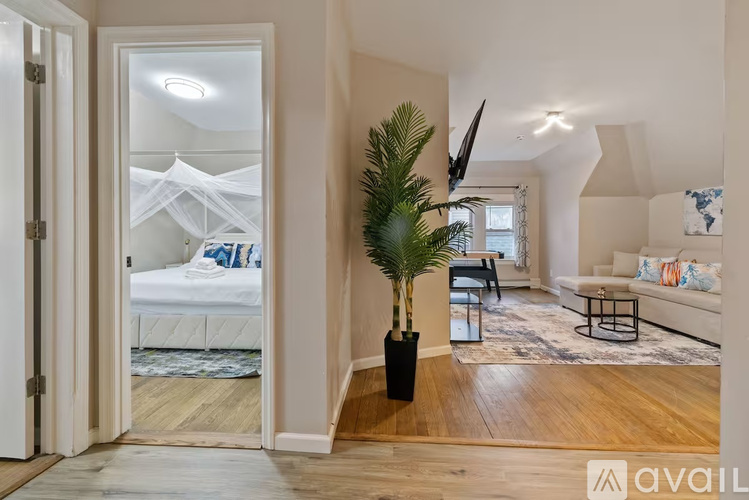 A bedroom with a large bed and a plant in a black pot.