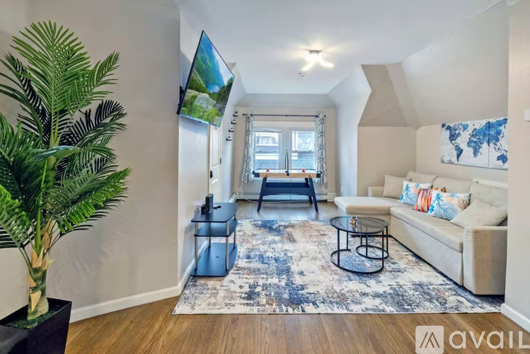 A living room with a couch, a chair, a coffee table, a rug, a plant, and a painting on the wall.
