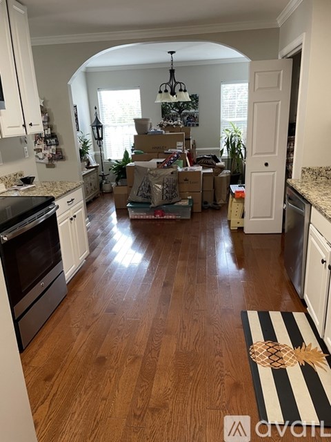 A kitchen with wooden floors and white cabinets is in the process of being moved into.