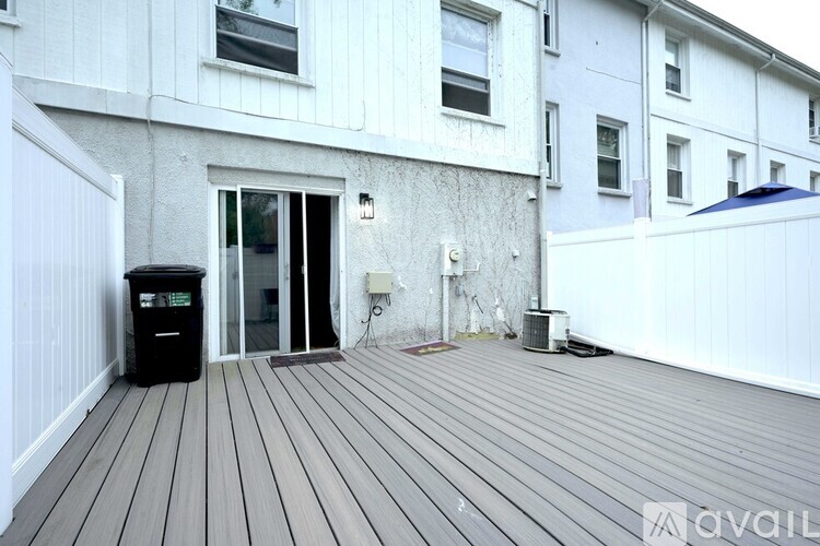A wooden deck leads to a white door on a building.