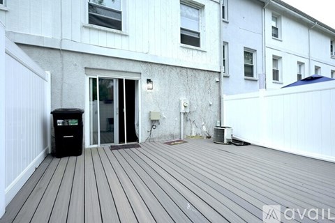 A wooden deck leads to a white door on a building.