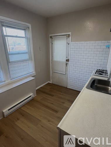 A kitchen with a white counter top and a white door.