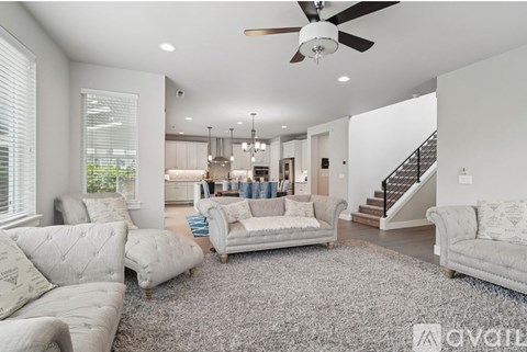 A living room with a grey rug and white furniture.