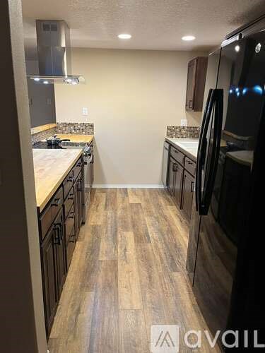 A kitchen with a black fridge and wooden floors.