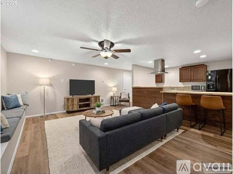 A living room with a grey couch and a wooden floor.