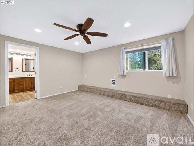 A spacious room with a ceiling fan and carpeted floor.
