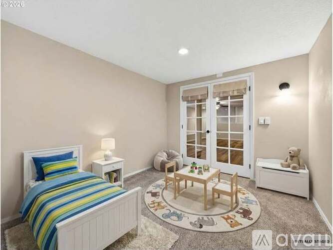 A cozy bedroom with a bed, a chair, a table, and a teddy bear.
