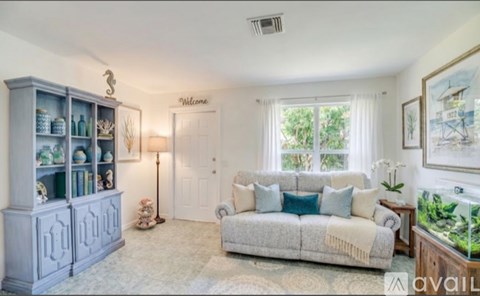 A living room with a grey cabinet, a white sofa, and a fish tank.