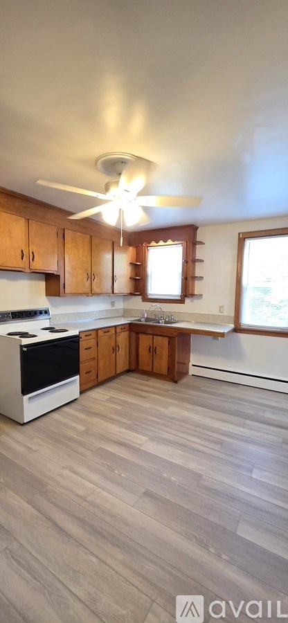 A kitchen with wooden cabinets and a ceiling fan.
