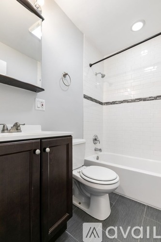 A white toilet sits in a bathroom next to a sink and a bathtub.