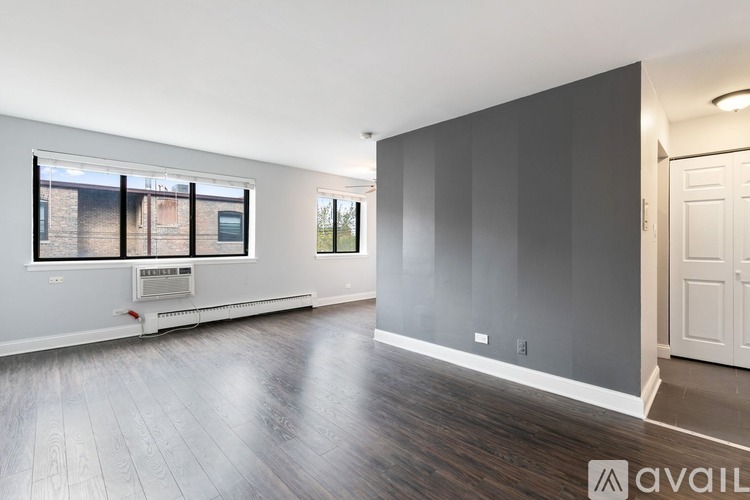 A spacious room with wooden flooring and a large window.