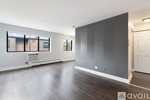 A spacious room with wooden flooring and a large window.