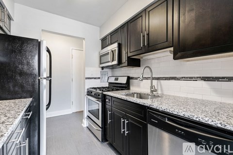 A kitchen with black cabinets and a granite countertop.