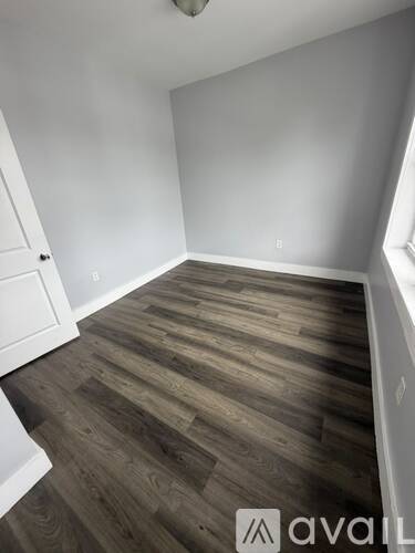 A room with wooden flooring and white walls.