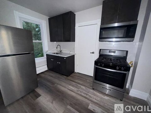 A kitchen with a stainless steel refrigerator, a microwave above the stove, and a sink with a faucet.