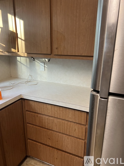 A kitchen with wooden cabinets and a stainless steel refrigerator.