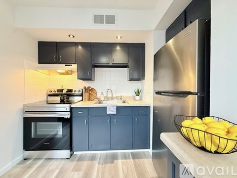 A modern kitchen with a stainless steel refrigerator and black cabinets.