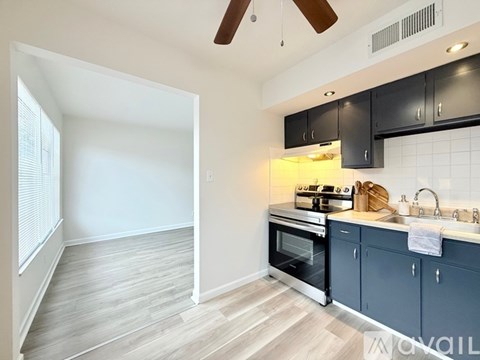 A kitchen with a black counter top and a fan on the ceiling.