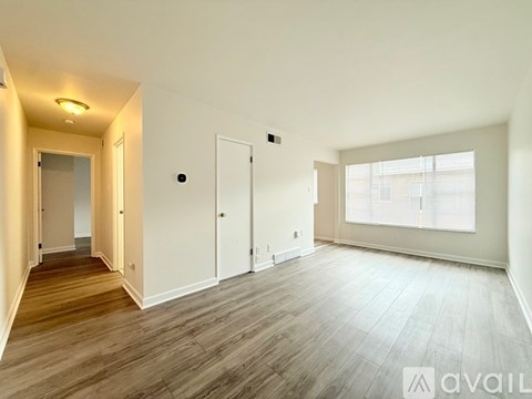 A spacious room with wooden flooring and white walls.