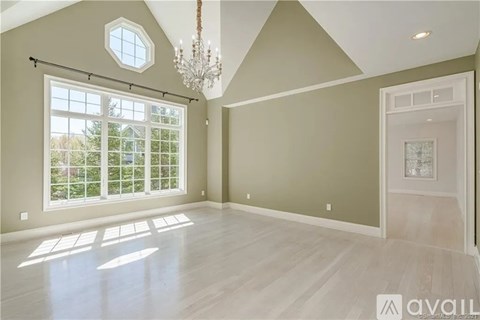 A spacious room with a large window and a chandelier.