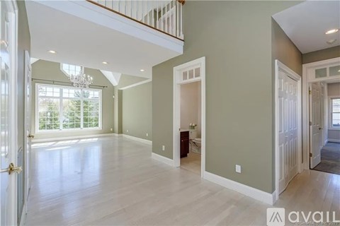 A spacious living room with a chandelier and hardwood floors.