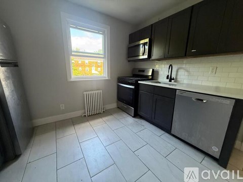 A kitchen with black cabinets and a white tile floor.