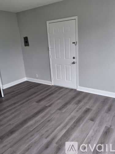 A room with a white door and grey flooring.