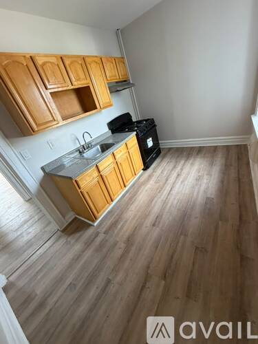 A kitchen with wooden cabinets and a black fridge.