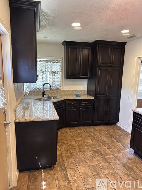 A kitchen with black cabinets and a granite countertop.