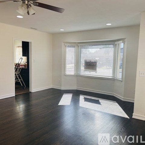 A room with a ceiling fan and a window with blinds.