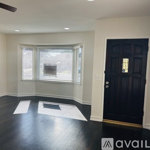 A room with a ceiling fan and a table in the middle.