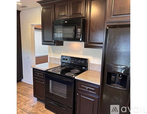 A kitchen with dark brown cabinets and black appliances.