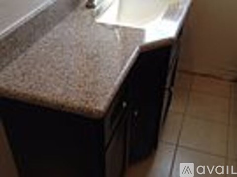 A granite countertop with a sink and a black cabinet.