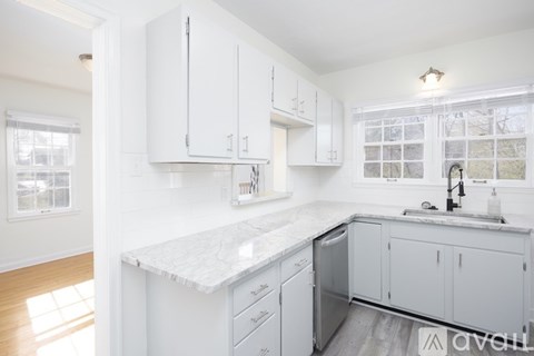 A kitchen with white cabinets and a marble countertop.