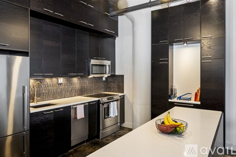 A modern kitchen with black cabinets and stainless steel appliances.