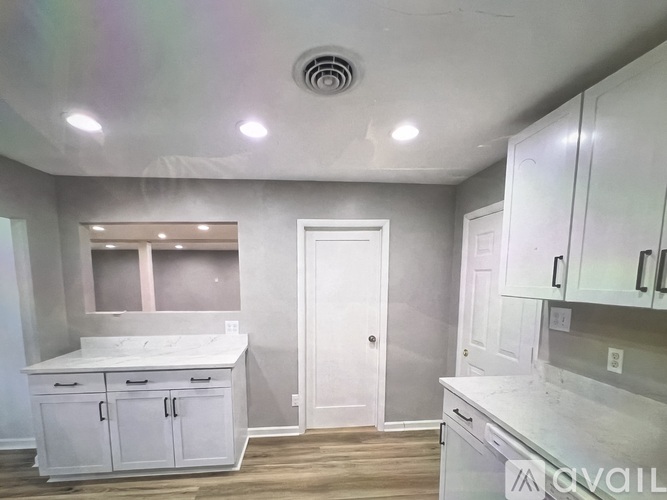 A kitchen with white cabinets and a door in the middle.
