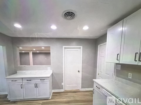A kitchen with white cabinets and a door in the middle.