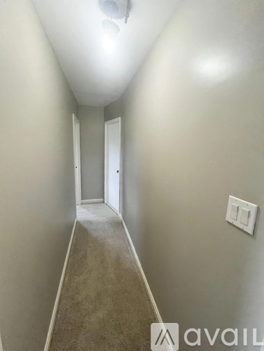 A long hallway with a carpeted floor and white walls.