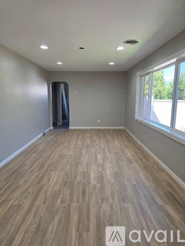 A room with wooden flooring and a window on the right side.