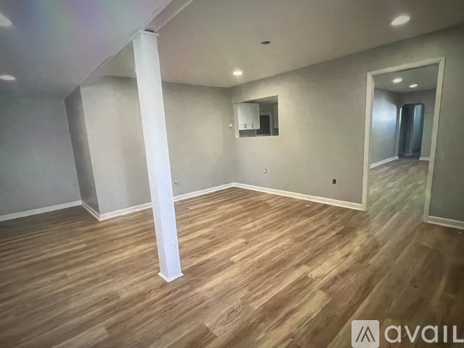 A spacious room with wooden flooring and a large mirror on the wall.